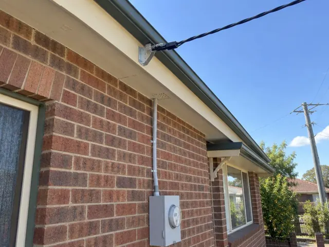 Brick house exterior with overhead service cable and bracket near the eaves in Maitland